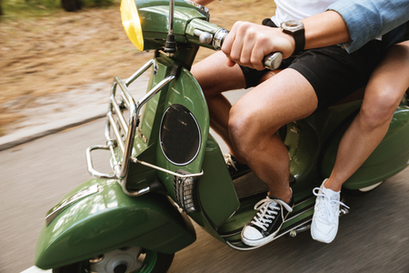 Cropped photo of young attractive loving couple man on scooter with girlfriend outdoorsの写真素材