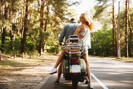 Back view image of young man on scooter with girlfriend outdoors.の写真素材