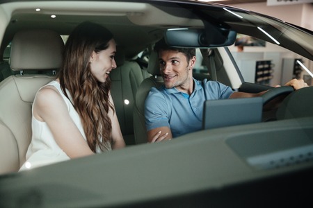Young couple sitting inside new car at dealership centerの写真素材