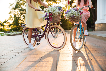 Cropped image of two young ladies walking outdoors on bicycles.の写真素材