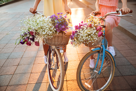 Cropped image of two young ladies walking outdoors on bicycles.の写真素材