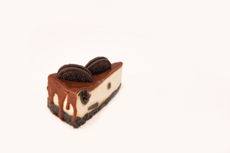 Close up of cheesecake with chocolate cream and cookie in it isolated over whiteの写真素材