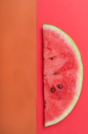 Slice of watermelon with stones on red backgroundの写真素材