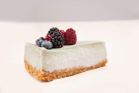 Side view of blue cheesecake with different berries on it isolated over whiteの写真素材