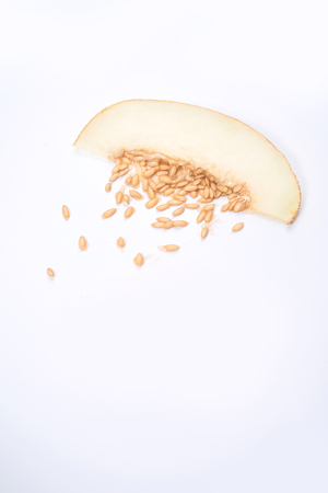 Shot of slice of yellow melon with stones isolated over whiteの写真素材