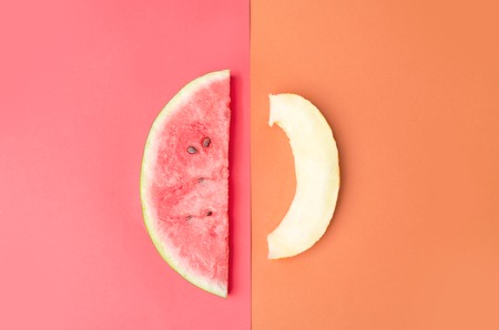 Slice of watermelon with stones on red background and melon isolated over orange backgroundの写真素材