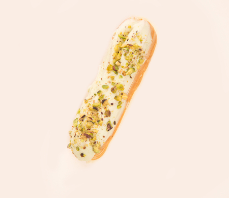 Close up of eclair with white cream and nuts isolated over whiteの写真素材