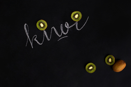 Fresh ripe kiwi fruit cut in slices with the inscription over black backgroundの写真素材