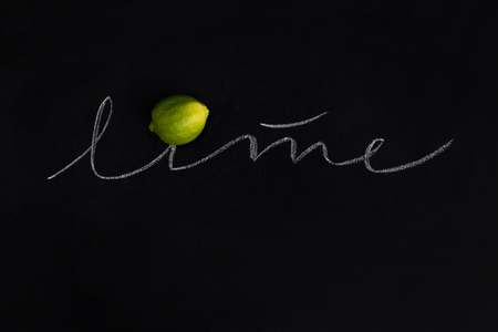 Ripe fresh lime with the inscription over black backgroundの写真素材