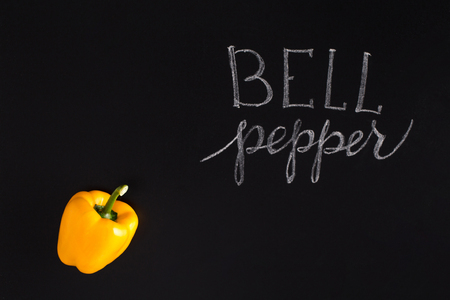 Shinny yellow bell pepper with the inscription over black backgroundの写真素材