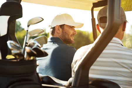 Two male golfers sitting in a cart and talkingの写真素材