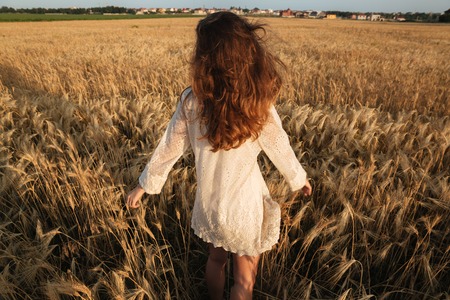 Back view image of amazing young lady in the field. Looking aside.の写真素材