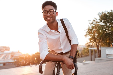 Image of concentrated young african man early morning with bicycle outdoors. Looking aside.の写真素材