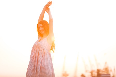 Beauty Smiling Ginger girl in dress posing on the sunset and looking at the cameraの写真素材