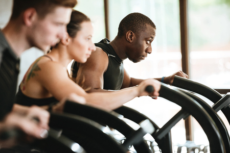 Group of multiracial young women and men exercising on a treadmill at the gymの写真素材