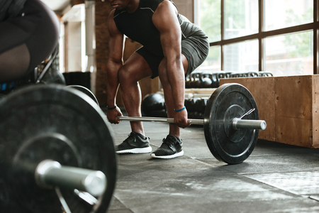 Cropped image of a young african sportsman lifting a barbell at the gymの写真素材