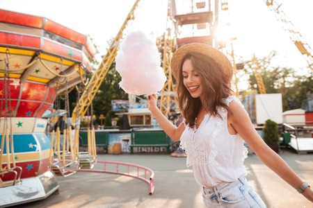 Happy smiling girl with cotton candy having fun at the amusement parkの写真素材