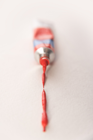 Tubes with watercolor paints of red colour making trace isolated over white backgroundの写真素材