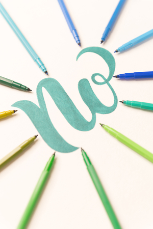 Green hand drawn phrase NO on white sheet between colorful markers. NO in frame of markersの写真素材