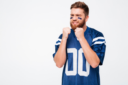 Hopeful male fan in blue t-shirt standing isolated over white background. Looking aside.の写真素材