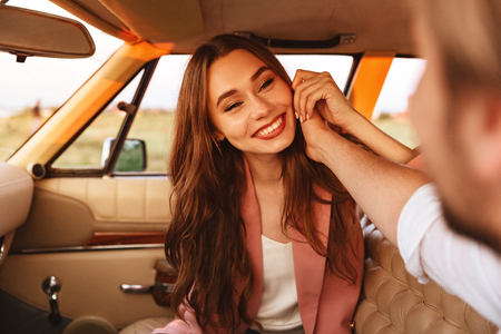 Happy brunette woman sitting inside a car with her boyfriendの写真素材