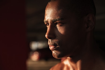 Close up portrait of a young concentrated half naked african sportsman looking away while standing...
