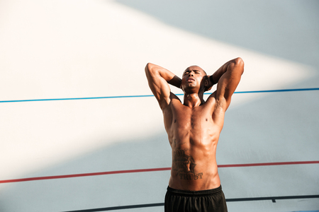 Portrait of a handsome african runner  with hands behind the head, resting after run on stadiumの写真素材
