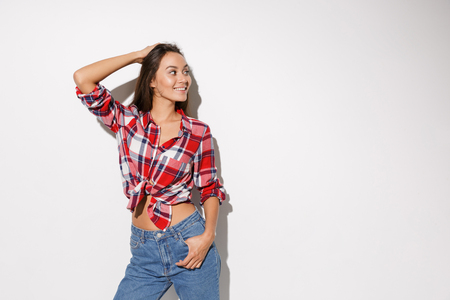 Young pretty girl with long brown hair, in checkered shirt posing, looking away, isolated on white backgroundの写真素材