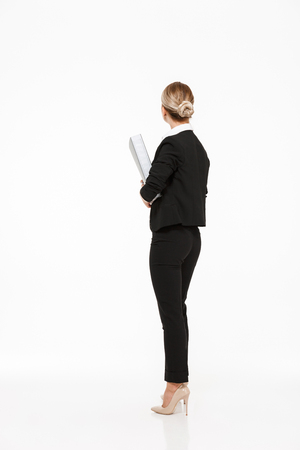 Vertical back view of blonde business woman holding big folder over white backgroundの写真素材