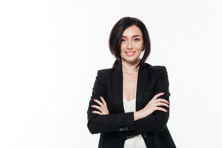 Portrait of a beautiful smiling businesswoman in a suit posing while standing with arms folded isolated over white backgroundの写真素材