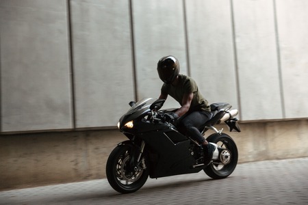 Portrait of a modern young afro american man in helmet riding motorbike outdoors