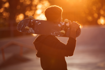 Young skateboarder man holding skateboard on his shoulders at public parkの写真素材
