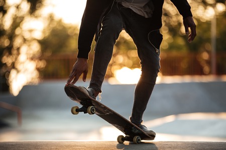 Cropped image of a young african male teenager riding on skateboard at a skate parkの写真素材