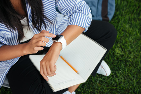 Cropped view of female student cheking time, outdoorの写真素材