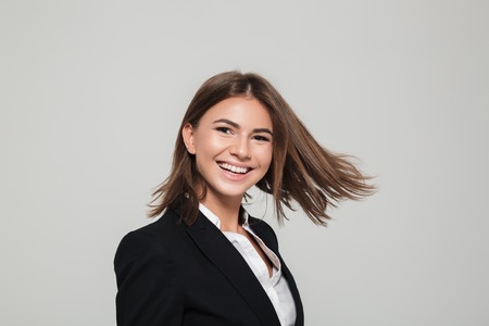 Close up portrait of a cheerful happy woman in suit looking at camera and laughing isolated over white backgroundの写真素材