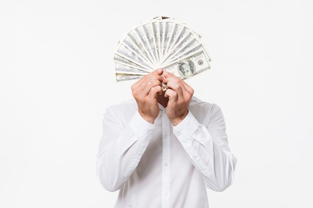 Portrait of a man in white shirt hiding behind a bunch of money banknotes isolated over white backgroundの写真素材