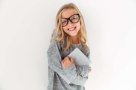 Close-up portrait of happy little girl in glasses hugging a book, looking at cameraの写真素材