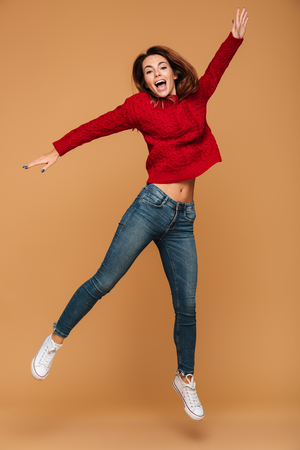 Image of smiling caucasian woman dressed in sweater jumping isolated. Looking camera.の写真素材
