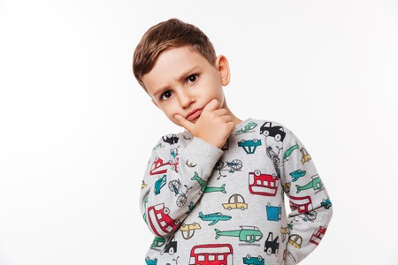 Portrait of a pensive cute little kid standing with hand on chin isolated over white backgroundの写真素材