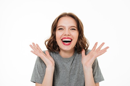 Close up portrait of an excited smiling woman with make-up laughing at camera and gesturing with hands isolated over white backgroundの写真素材