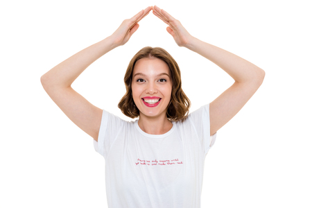 Image of happy pretty caucasian woman standing isolated. Looking camera gesturing with hands over head.の写真素材
