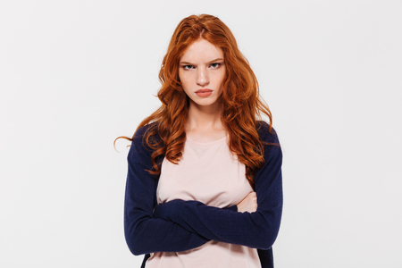 Image of angry pretty young redhead lady standing isolated over white wall background with arms crossed. Looking camera.の写真素材