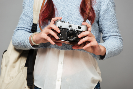 Cropped photo of girl standing isolated grey background holding camera in hands.の写真素材