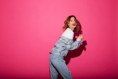 Photo of laughing young woman isolated over pink background. Looking camera.
