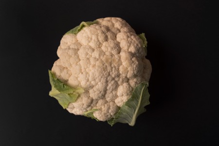 Close up of a fresh cauliflower isolated over black backgroundの写真素材