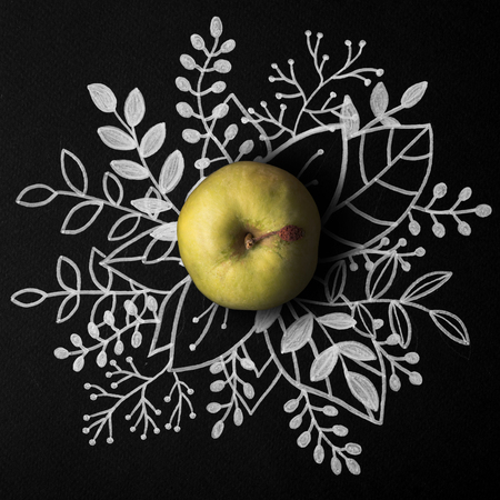 Green apple over outline floral hand drawn backgroundの写真素材