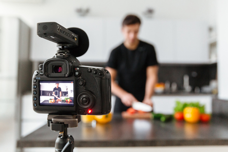 Close up of a video camera filming young male blogger at the kitchenの写真素材