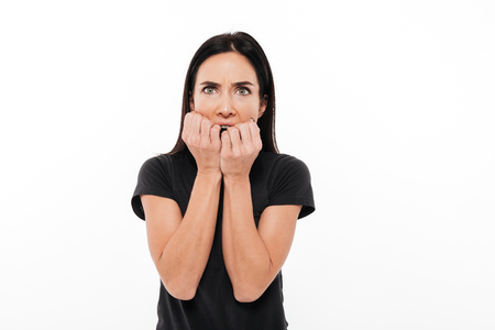 Portrait of a frightened woman holding hands at her face and looking at camera isolated over white backgroundの写真素材