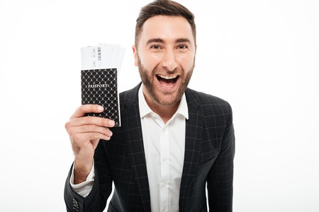 Close up portrait of a happy excited man showing passport with flying tickets isolated over white backgroundの写真素材