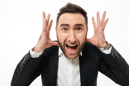 Close up portrait of a mad young bearded man looking at camera and shouting isolated over white backgroundの写真素材